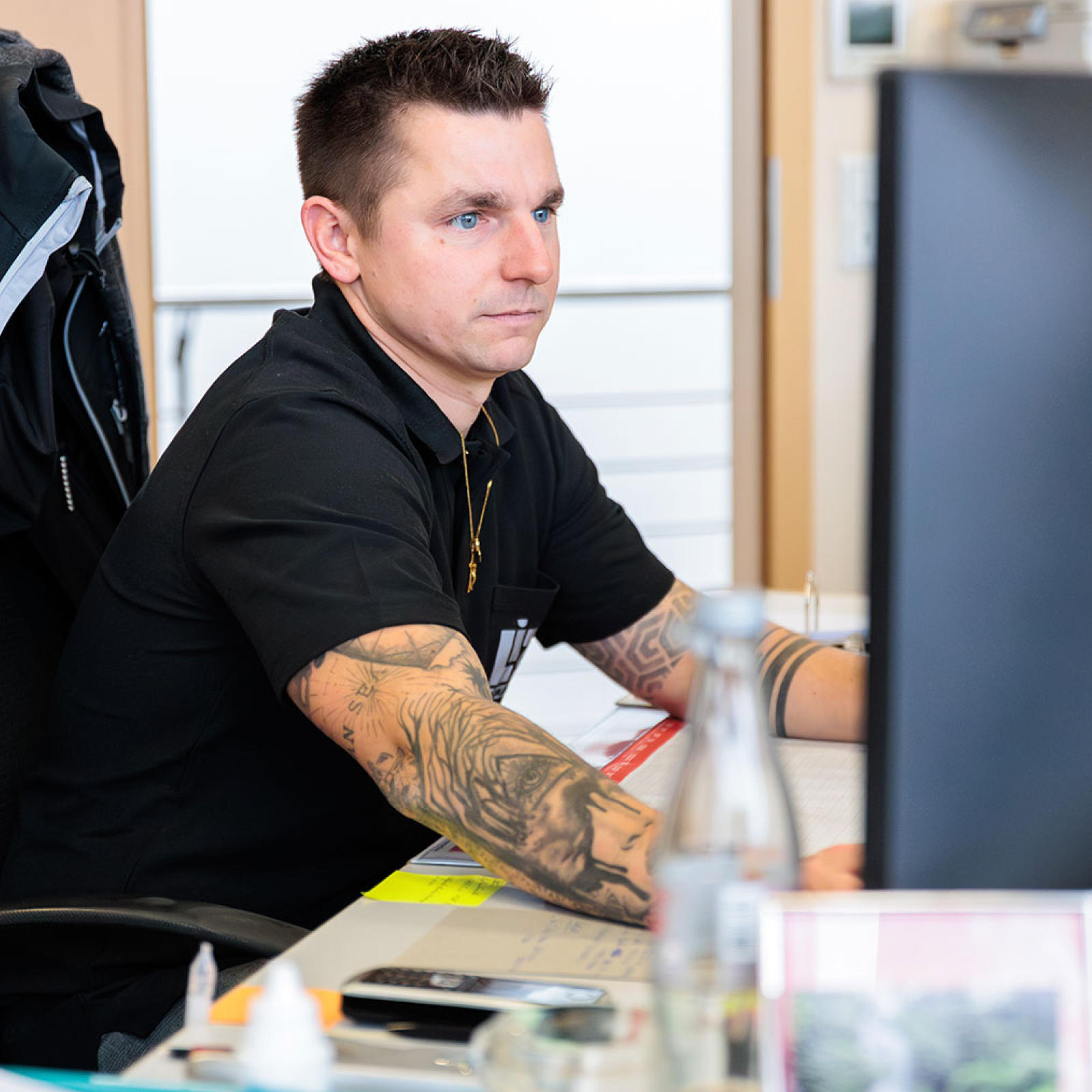 Ein Mitarbeiter sitzt am Schreibtisch vor einem Rechner und bearbeitet ein Angebot.