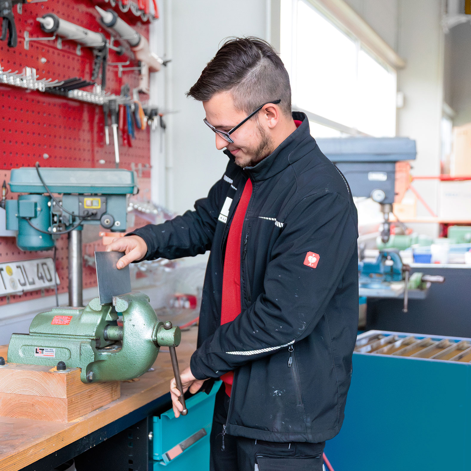 Ein Mitarbeiter steht an einer Werkbank und bearbeitet ein Blechstück.