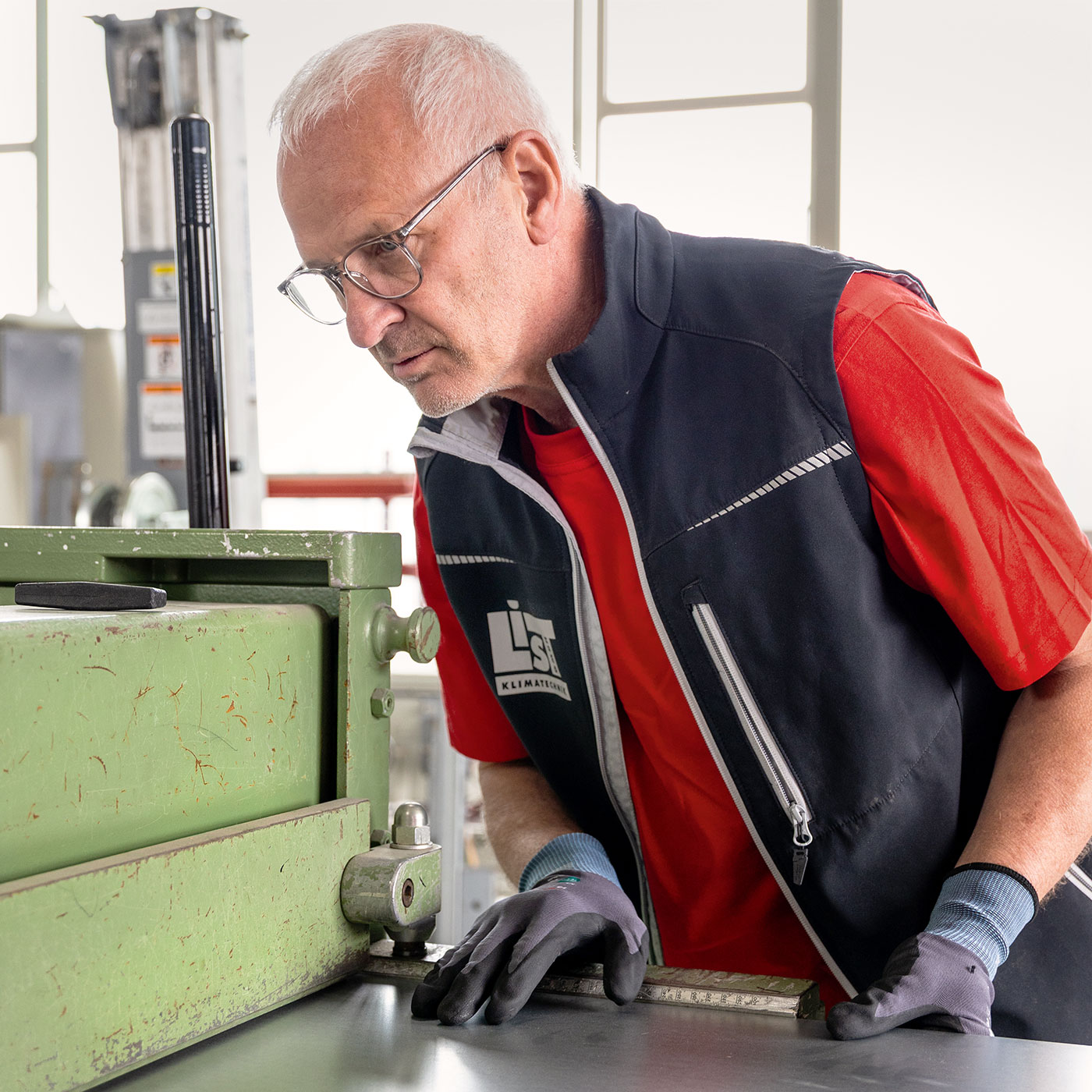 List-Klimatechnik-Mitarbeiter schiebt Blechstueck in Schneidemaschine